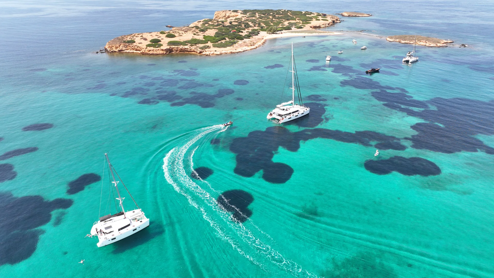 Luxury catamarans anchored in the vibrant turquoise waters of the Saronic Gulf just off the coast of Athens.