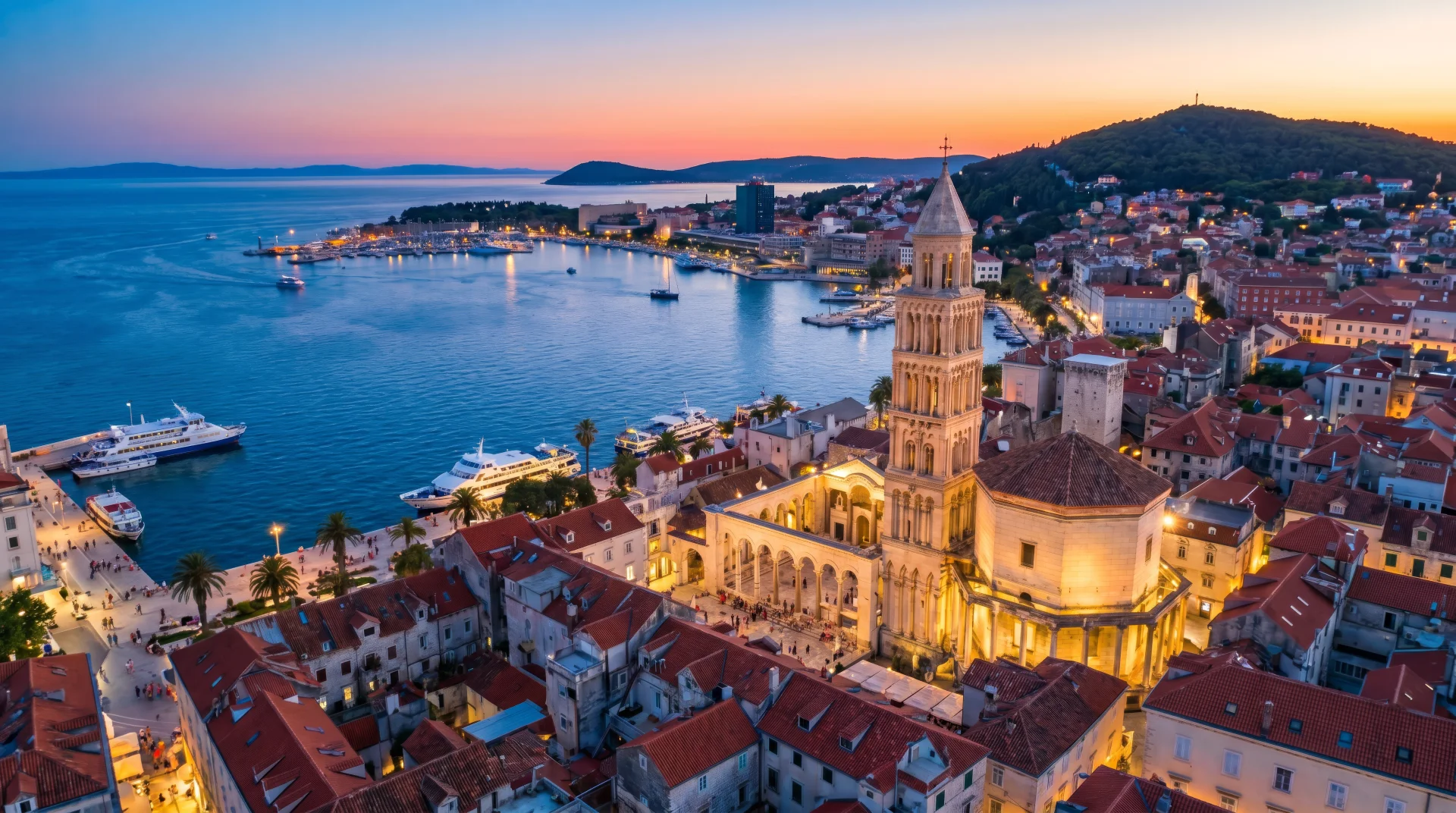 Stunning twilight aerial view of Split's illuminated Old Town, highlighting the iconic bell tower and the bustling waterfront marina.