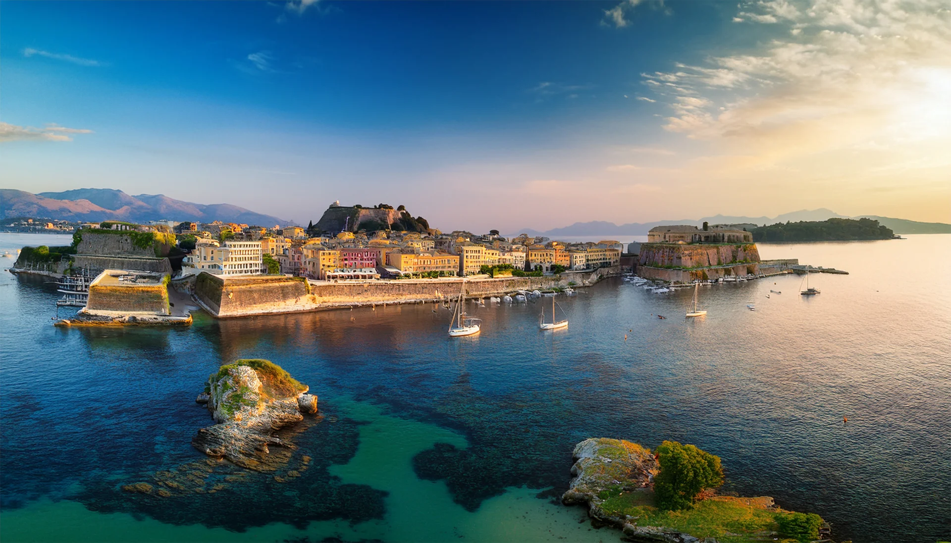 Sunset illuminating the historic Old Fortress of Corfu Town, offering a majestic anchorage for visiting yachts.